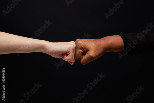 close up of diverse mixed race people making a fist bump on black background, do a fist pump together after good deal. success and teamwork concept.