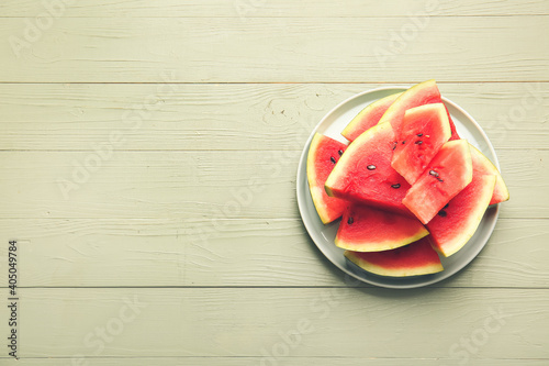 Plate with slices of ripe watermelon on wooden background
