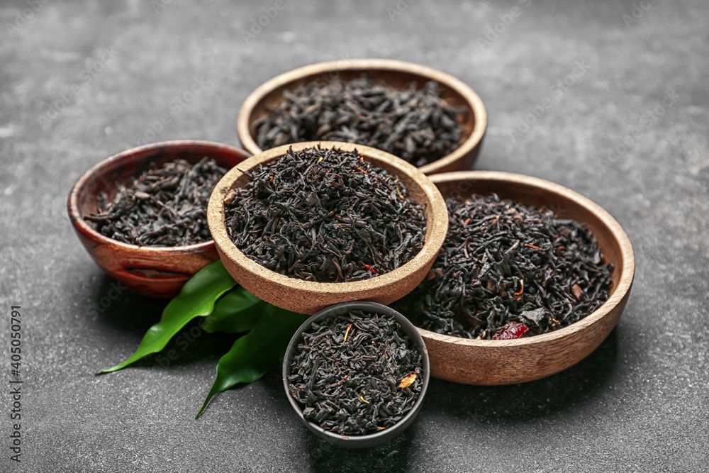 Dry black tea leaves in bowls on dark background Dry black tea leaves in bowls on dark background