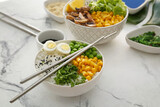 Bowls with tasty rice, eggs and vegetables on light background