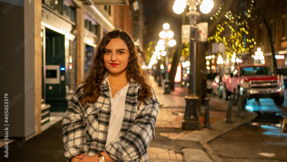 イルミネーションの輝く街中でカメラ目線でデートを楽しむラテン系の女性