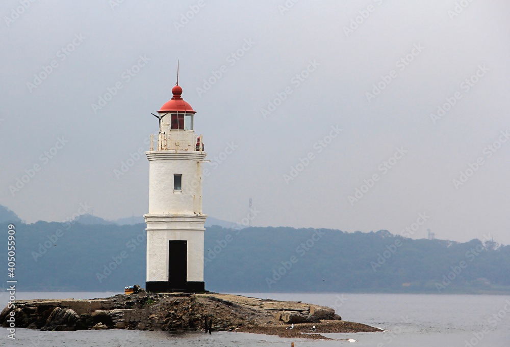 Lonely lighthouse on a stone road in the middle of the sea with mountain view