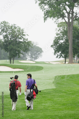 Rear view of two men walking on golf course