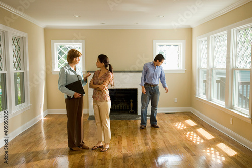 Hispanic couple talking to real estate agent in house photo