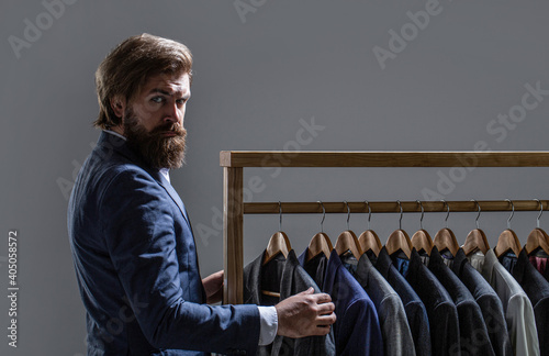 Tailor, tailoring. Men's suit, tailor in his workshop. Elegant man's suits hanging in a row. Luxury mens classic suits on rack in elegant men's boutique photo