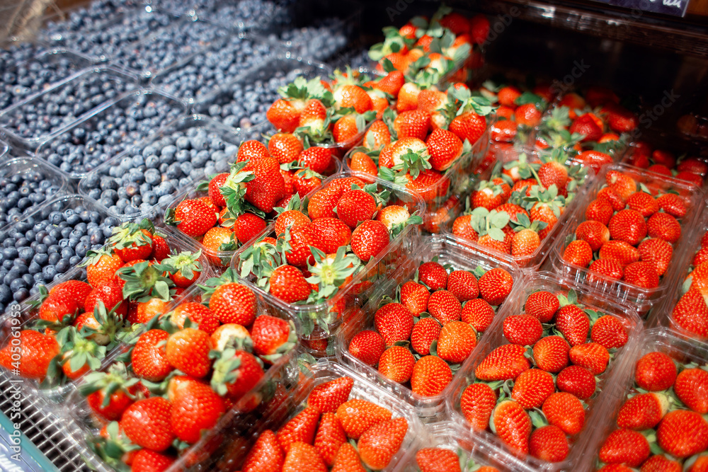 Many blueberries and strawberries in containers on the counter in an exotic fruit store