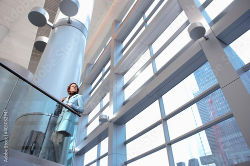 Caucasian businesswoman leaning on railing in lobby photo