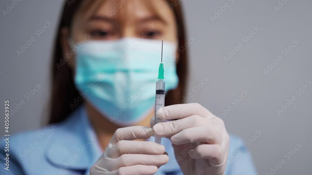female doctor holding syringe with Coronavirus (Covid-19) vaccine for injection test