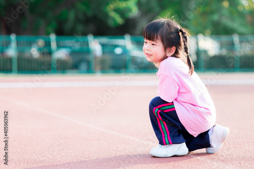 Obraz na plátně Kindergarteners squat in a sports ground, pretending to run