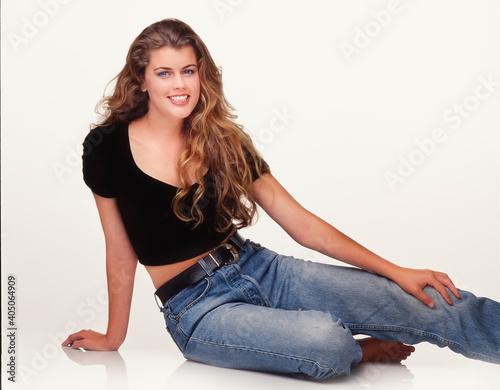 Portrait of beautiful young woman sitting on white backdrop