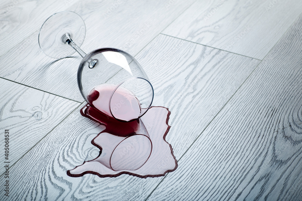 Wooden floor with overturned glass of red wine. Spilled wine on a wooden laminate (parquet) floor with moisture protection.