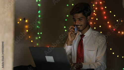 Young indian man working on laptop at home over lighting background