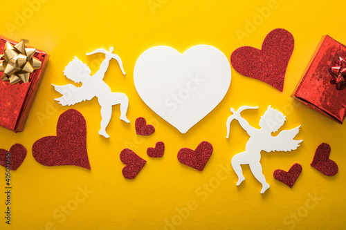 Flying cupid silhouette with hearts, happy Valentine's Day banners, paper art style. Amour on yellow paper