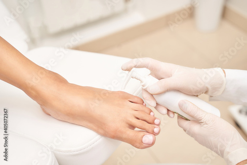 Pedicure nail spa procedure. Foot manicure. Salon master. Polish woman leg. Hands in gloves. Light background. Massage service. Healthy toe cleaning. Pink pastel color. Dermatology cream
