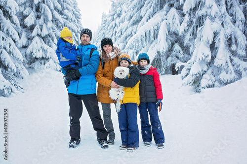 Happy family with three children and puppy dog, hiking in mountains wintertime, lots of snow, beautiful winter