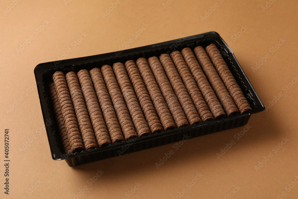 Plastic box with chocolate wafer rolls on brown background Plastic box with chocolate wafer rolls on brown background