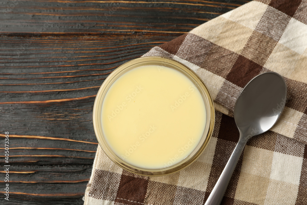 Towel, spoon and bowl with condensed milk on wooden background Towel, spoon and bowl with condensed milk on wooden background