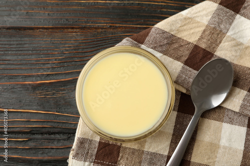 Fotografía Towel, spoon and bowl with condensed milk on wooden background