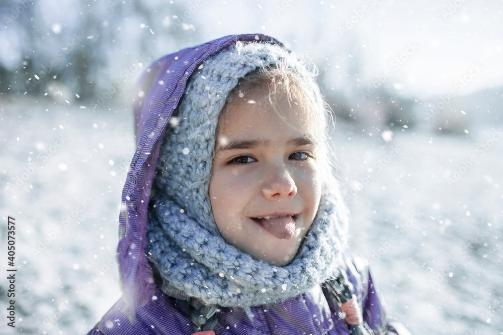 Little pretty girl in knitted grey hat enjoying first winter snow and tasting it with tongue, kid walking on the beach in winter, love keep you warm, happy real people. Outdoors lifestyle