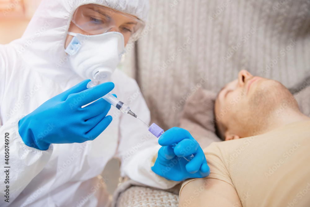 Concept Vaccination of people against dangerous virus Covid 19 coronavirus. Close-up nurse in protective suit holding syringe and vaccine Concept Vaccination of people against dangerous virus Covid 19 coronavirus. Close-up nurse in protective suit holding syringe and vaccine