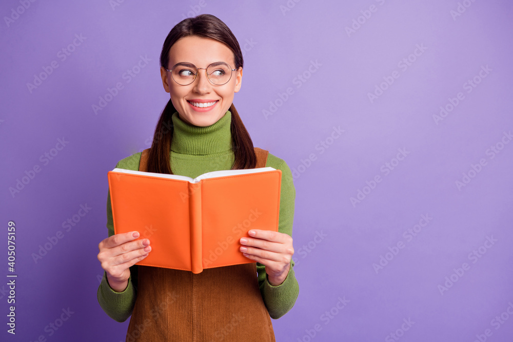 Obraz premium Portrait of lovely brainy cheery girl reading book looking aside ad solution isolated over pastel violet color background
