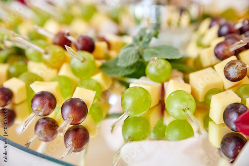 Smorgasbord. Canapes with cheese  bacon  green and red grapes on the glass plate. Close-up  selective focus