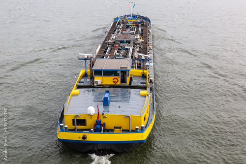 Top view onto a yellow and blue tank barge on a river