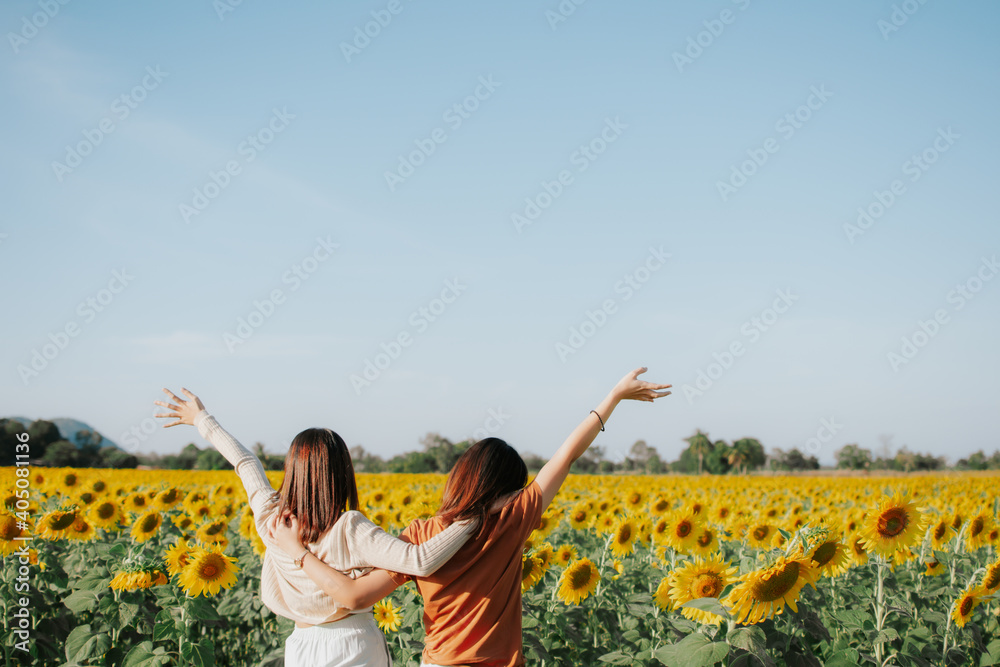 Foto de Two women are standing in a field of sunflower and hugging each ...