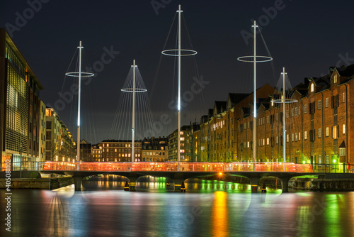 Eliasson Cirkelbroen (Five Circles Pedestrian Bridge) across a canal illuminated at night in a modern residential area. The play of light on the water results in a cosy atmosphere. Copenhagen, Denmark photo