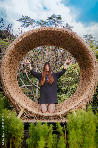 Beautiful asian Woman sitting with Yoga pose on a wooden circle cruve Bench outdoor with smile photo