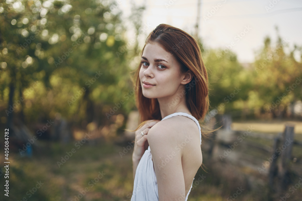 portrait of a red-haired woman in nature in the garden and trees In the background summer vacation portrait of a red-haired woman in nature in the garden and trees In the background summer vacation