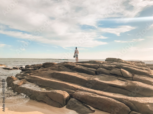 Man standing on rock beside ocean photo