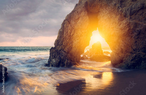 Arched rock formation on beach during sunset