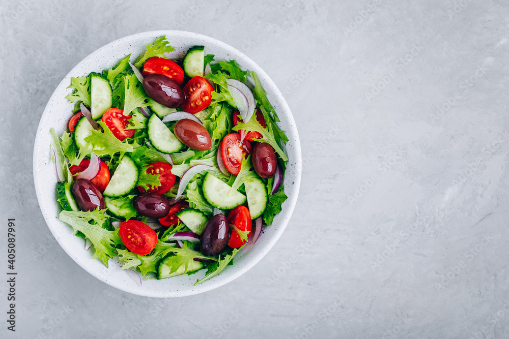 Healthy green salad with fresh tomato, cucumber, red onion, olives and lettuce in bowl Healthy green salad with fresh tomato, cucumber, red onion, olives and lettuce in bowl