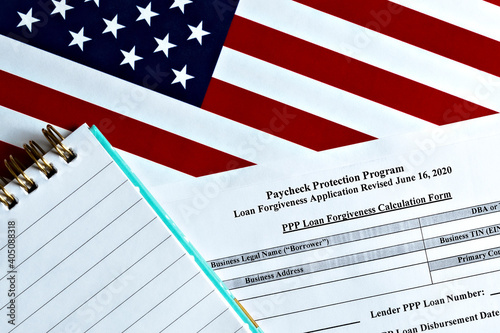 close-up of paycheck protection program loan forgiveness application form revised topview, on a background of United States flag. paycheck protection program new round.