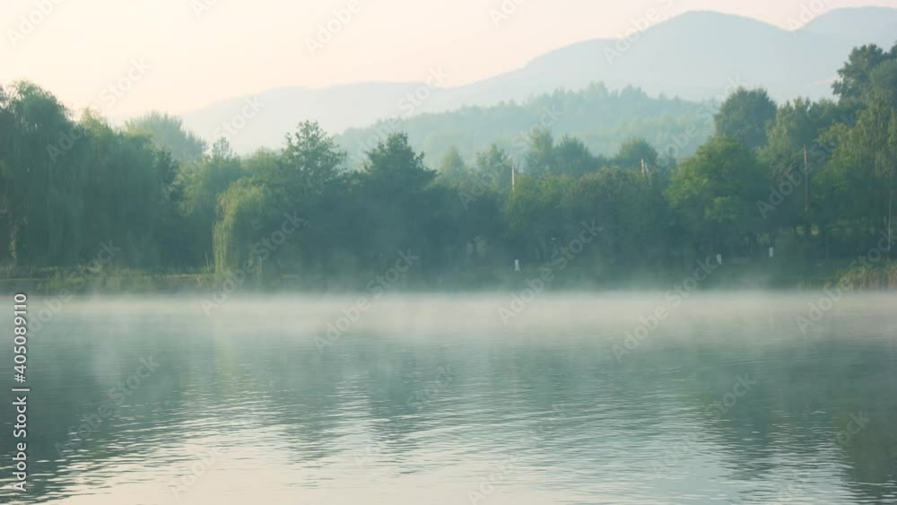 Foggy lake in the early morning. Misty mountain lake at sunrise. Picturesque morning scene.