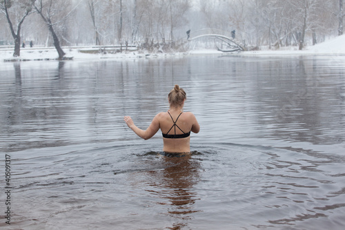 Swimming in the winter. Woman enters ice bathing water