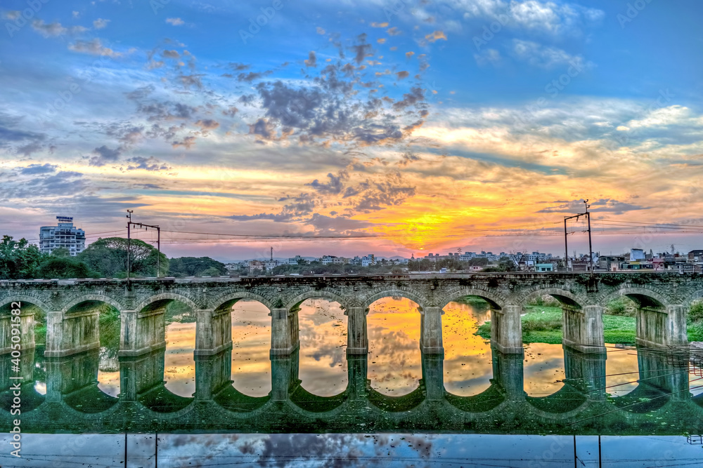 Beautiful Sunset behind an old stone arched rail bridge reflection and ...