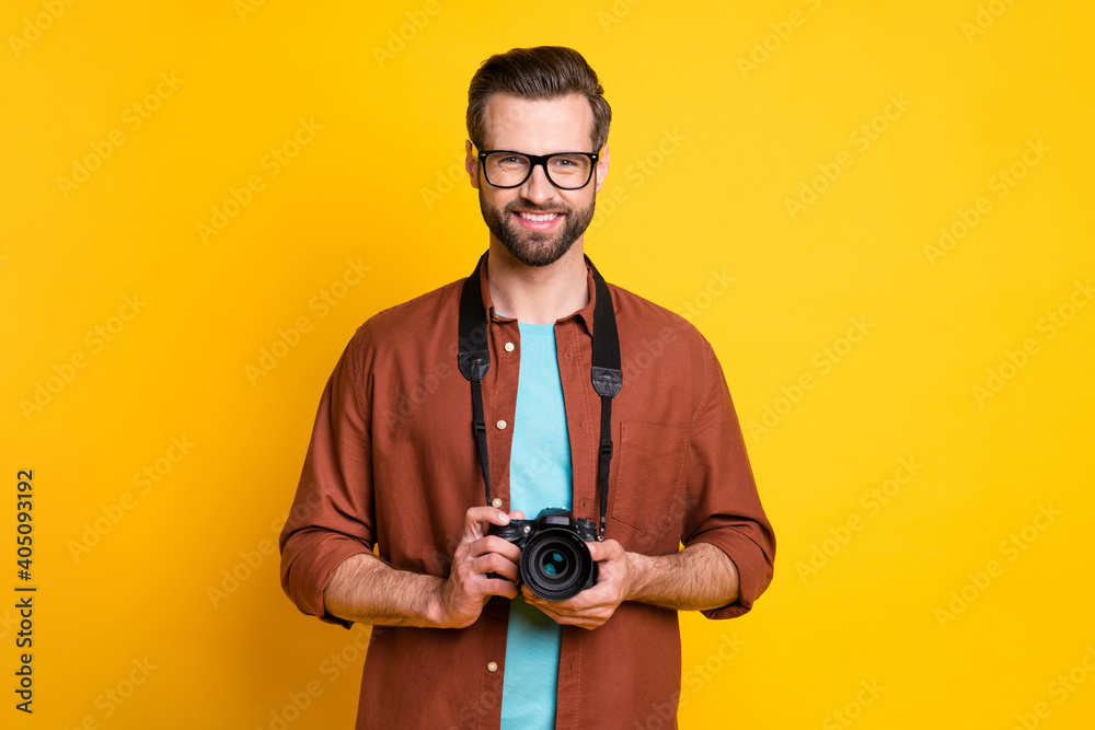 Photo portrait of bearded man in glasses keeping camera taking photo isolated on vivid yellow color background Photo portrait of bearded man in glasses keeping camera taking photo isolated on vivid yellow color background