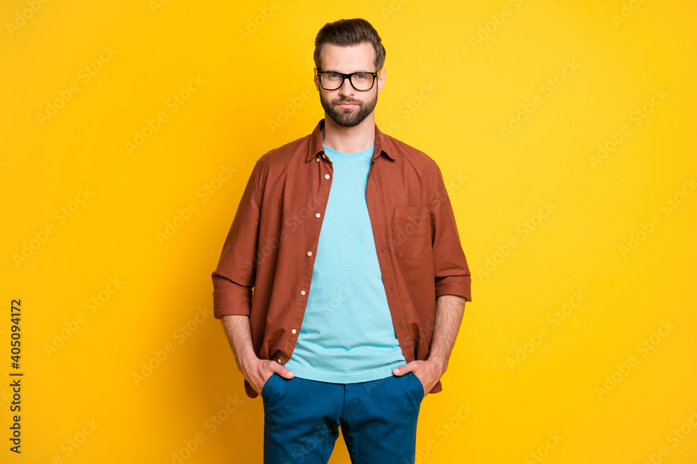 Fototapeta premium Photo portrait of clever serious businessman in glasses in casual clothes hands in pockets isolated on bright yellow color background