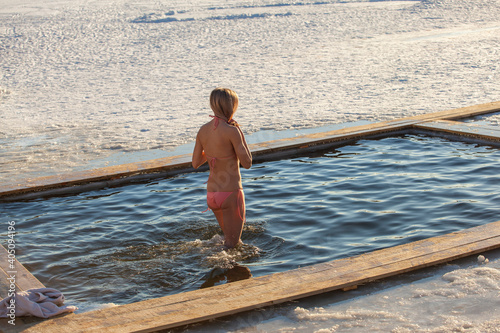 Swimming in the winter. Woman enters ice bathing water