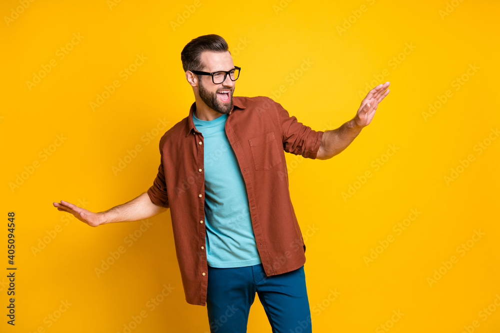 Photo of charming funky optimistic young man raise hands look dance free-time isolated on yellow color background Photo of charming funky optimistic young man raise hands look dance free-time isolated on yellow color background