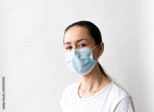 Head and shoulders portrait of female doctor wearing protective mask and looking at camera posing against white background  copy space
