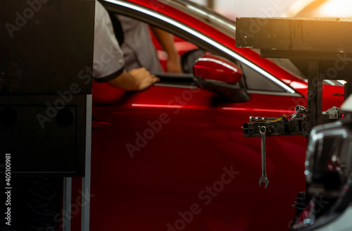 Wrench hang on tools rack in workshop on blurred mechanic technician and red SUV car parked in auto repair shop. Red car in garage for repair and maintenance service. Car check-up at service station.