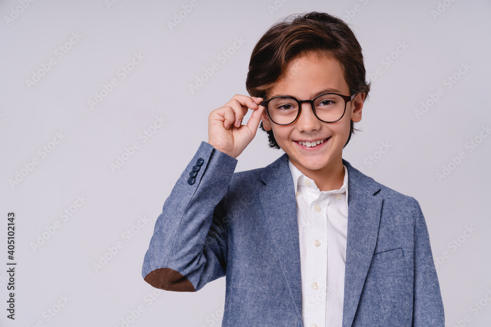 Close up portrait of a charming young boy in glasses and formal suit like future businessman isolated over grey background Close up portrait of a charming young boy in glasses and formal suit like future businessman isolated over grey background