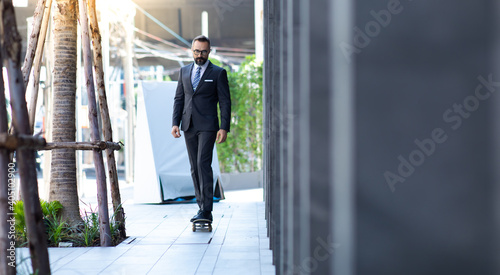Stylish hipster bearded man skater riding a longboard go to working at the city. © NVB Stocker