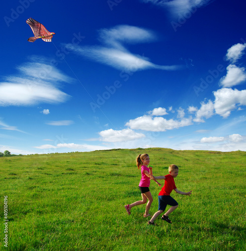  boy and girl run with kite in the field