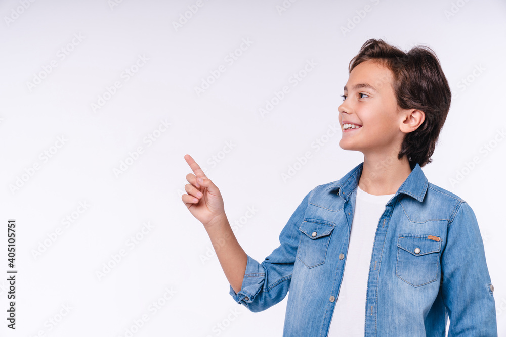 Smart little 10s boy in casual attire pointing at copy space isolated over white background Smart little 10s boy in casual attire pointing at copy space isolated over white background