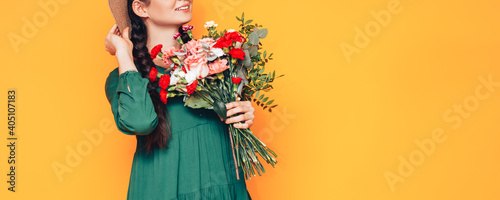 Foto Woman holding a large bouquet of flowers in a green dress on a yellow background