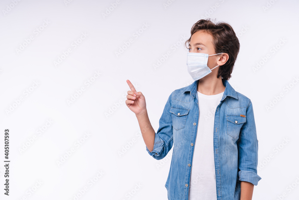 Young caucasian kid pointing at copy space in medical mask against coronavirus isolated over white background Young caucasian kid pointing at copy space in medical mask against coronavirus isolated over white background